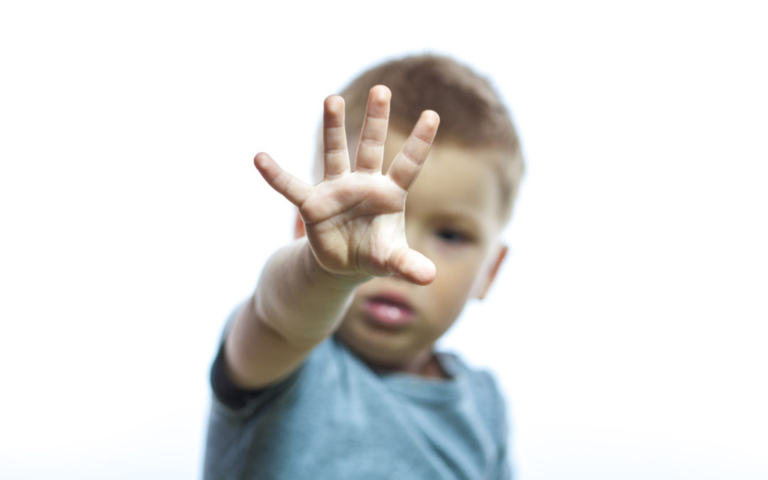 Portrait of little handsome boy showing stop with his hand, isolated on white background.